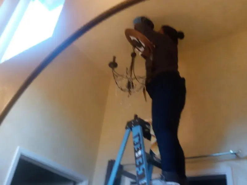 Electrician installing a chandelier in a Bowling Green residence